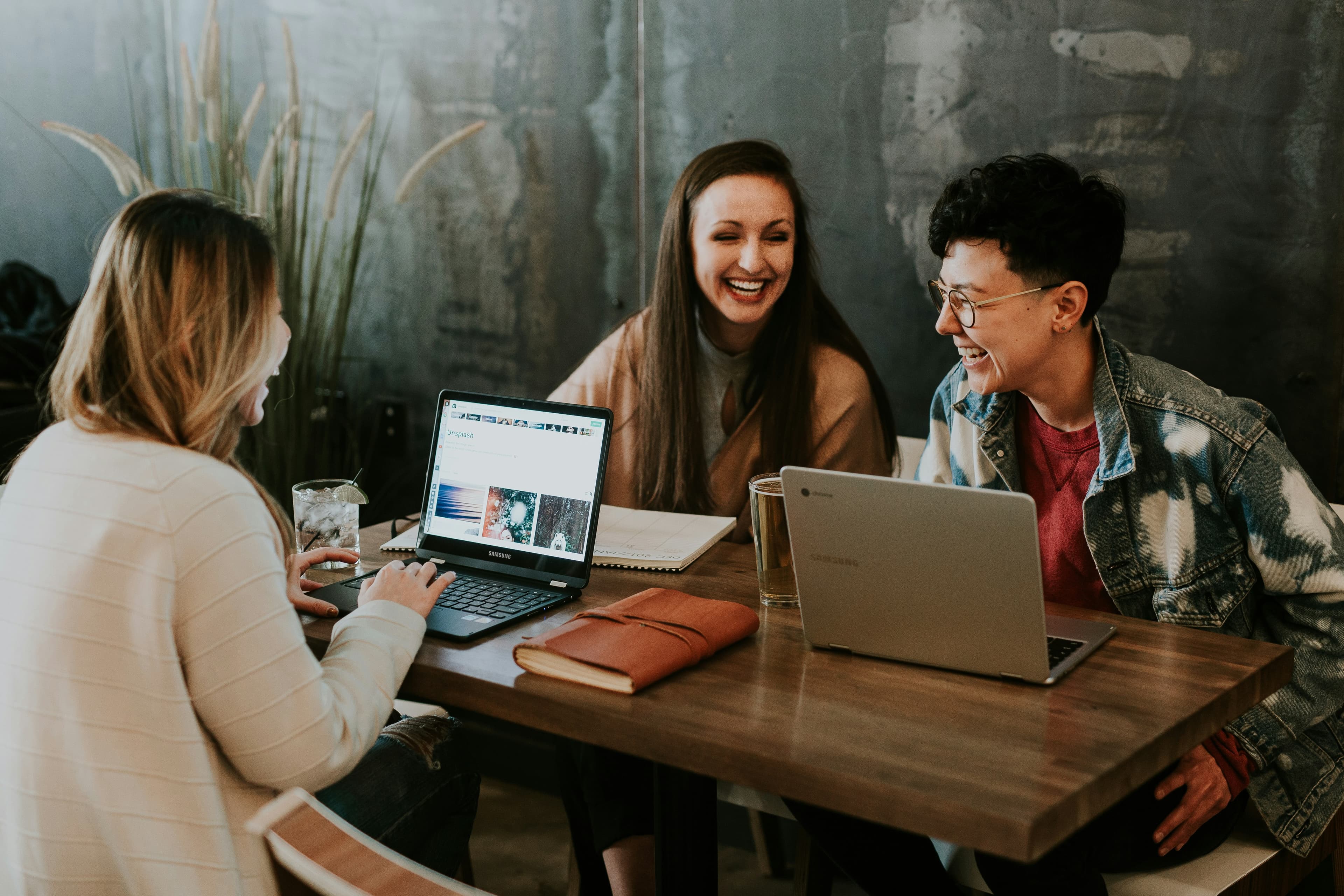 Three ecommerce researchers working together on laptops, reviewing a live list of Shopify stores and product catalogs for winning product ideas to sell online