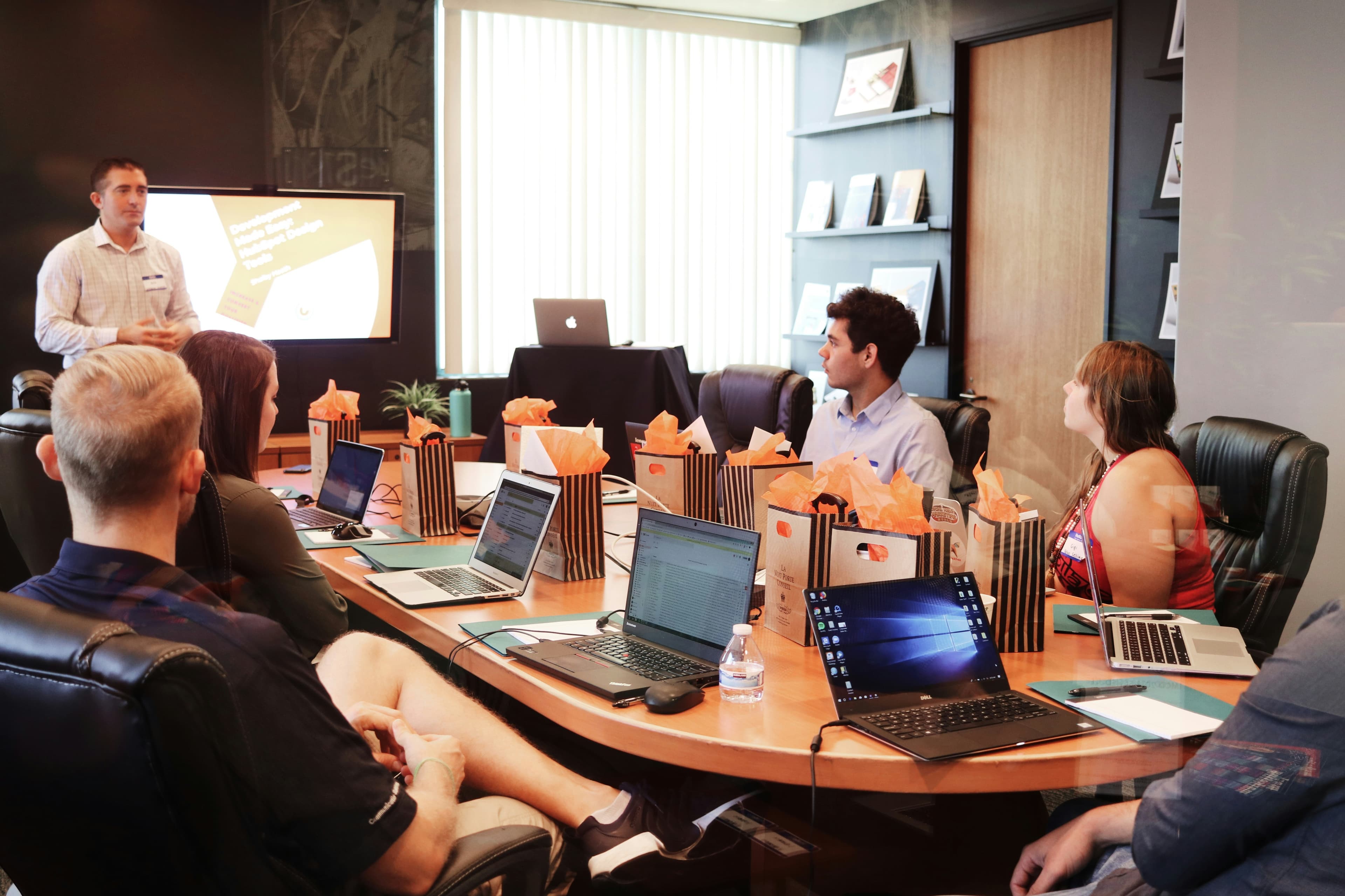 Ecommerce strategy team sitting around a conference table with open laptops, discussing product research results and planning a list of Shopify stores worth studying for winning product ideas
